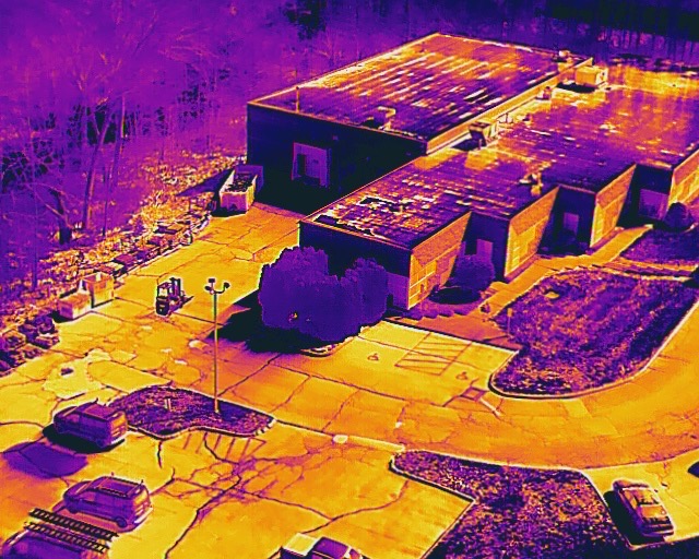 Thermal aerial survey revealing building rooftops, parking layout, and perimeter access points